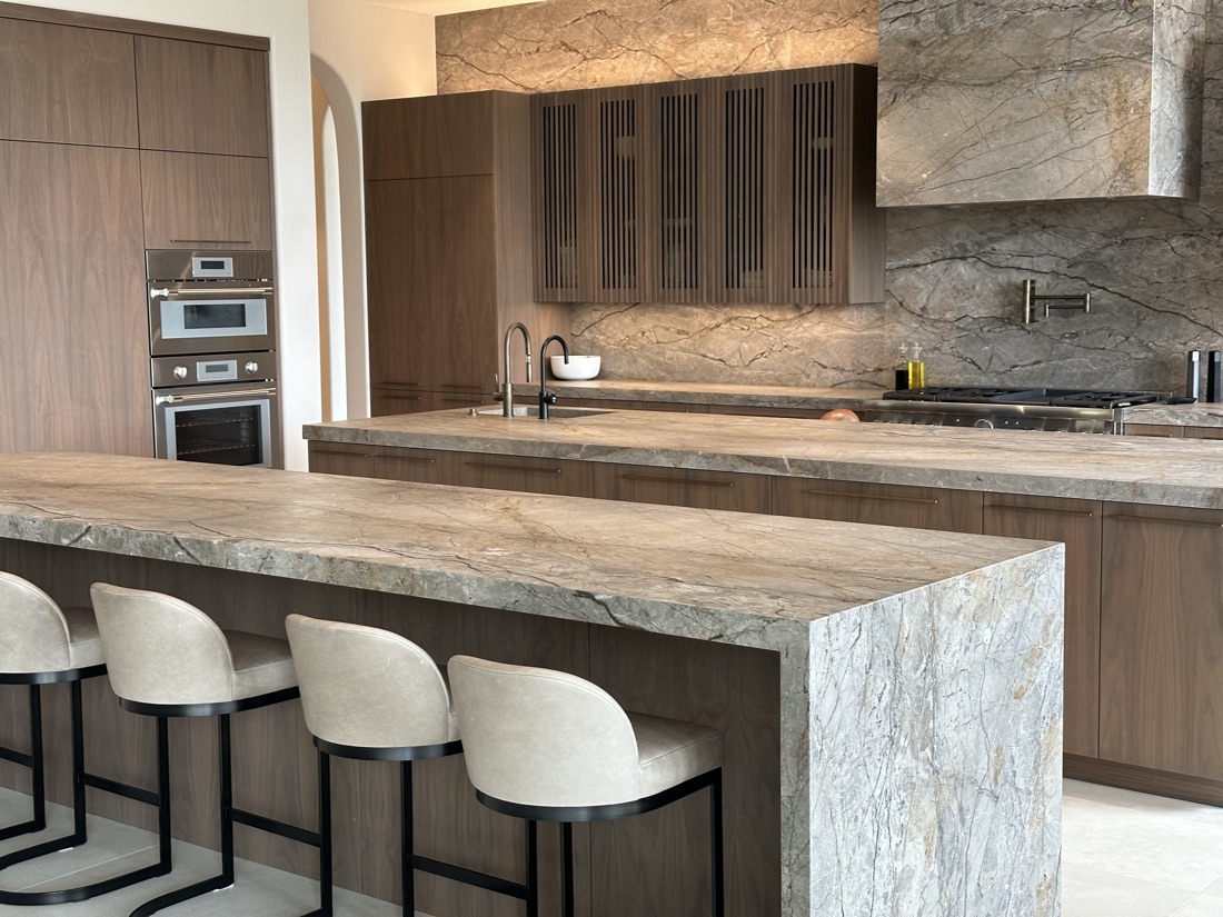 Custom kitchen with walnut cabinetry, a marble waterfall island, and a stone slab backsplash, San Diego