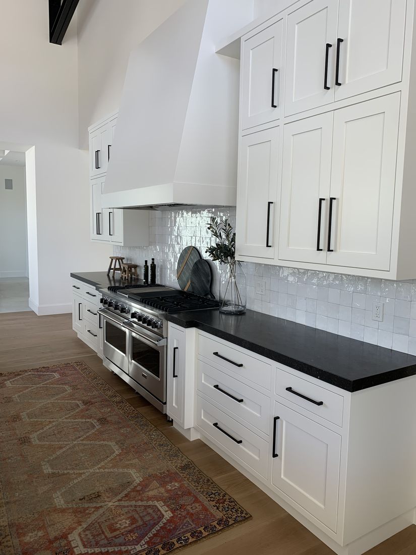 Custom white kitchen with a professional range and black stone countertops, San Diego